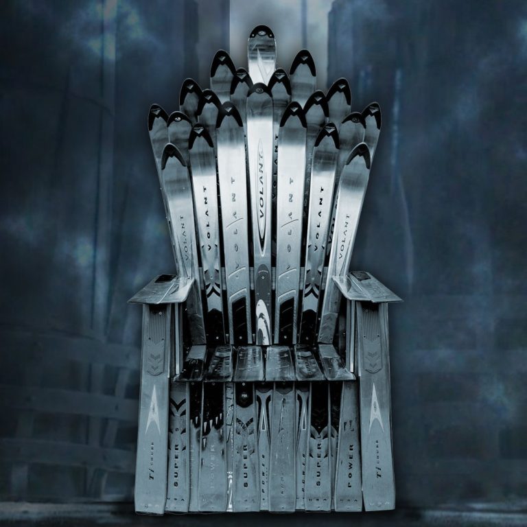 Throne style ski chair built from layered stainless steel skis against a dark misty castle backdrop