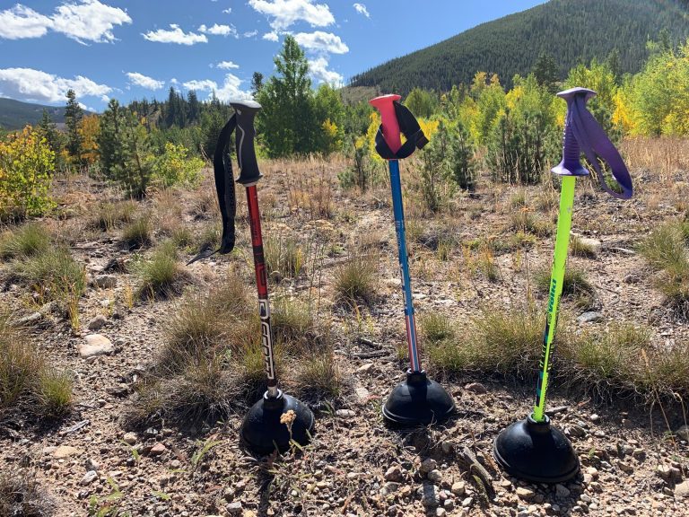 Three ski pole plungers in red, blue and green standing in a mountain meadow