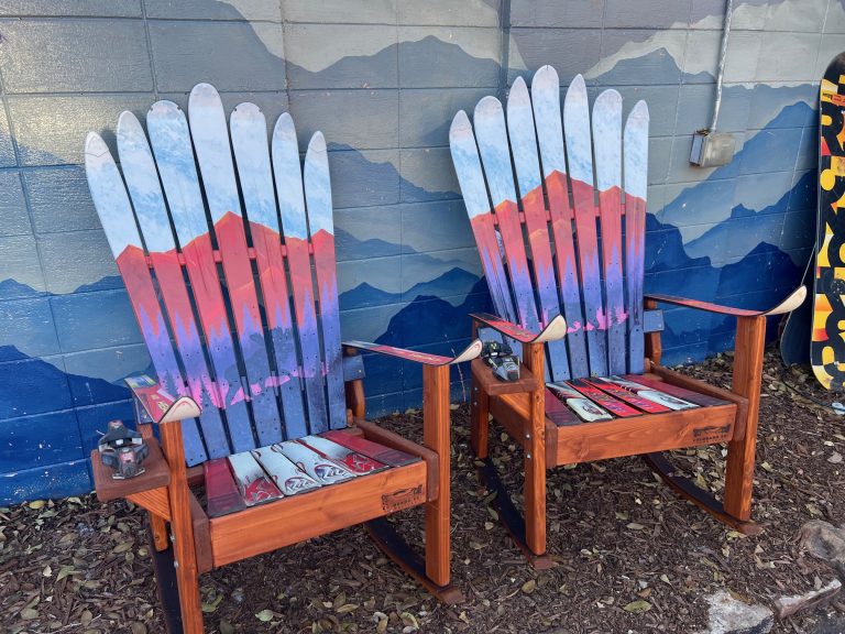 Two ski chairs airbrushed with red and purple sunset gradients, backed by a mountain wall