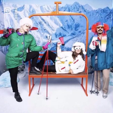 Orange ski lift bench used as a party photo booth prop with three people in ski gear