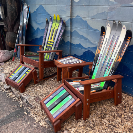 Ski Rocker and Ottoman Set, Angled View Two ski rocking chairs with matching ski ottomans and a side table built from retired downhill skis