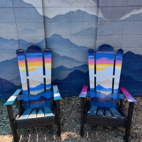 Sunset Alpine Ski Chair Pair, Front View Two compact Alpine ski chairs with orange and gold sunset murals fading into blue mountain ridges