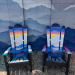 Two compact Alpine ski chairs with orange and gold sunset murals fading into blue mountain ridges