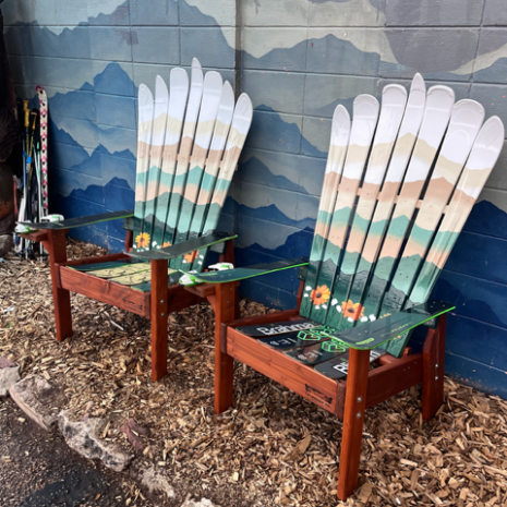 Set of two Adirondack ski chairs with a sage green mountain mural and orange sunflowers